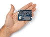 Arduino UNO Q board held in hand, demonstrating its compact size for portable robotics and embedded AI projects, on a white background.