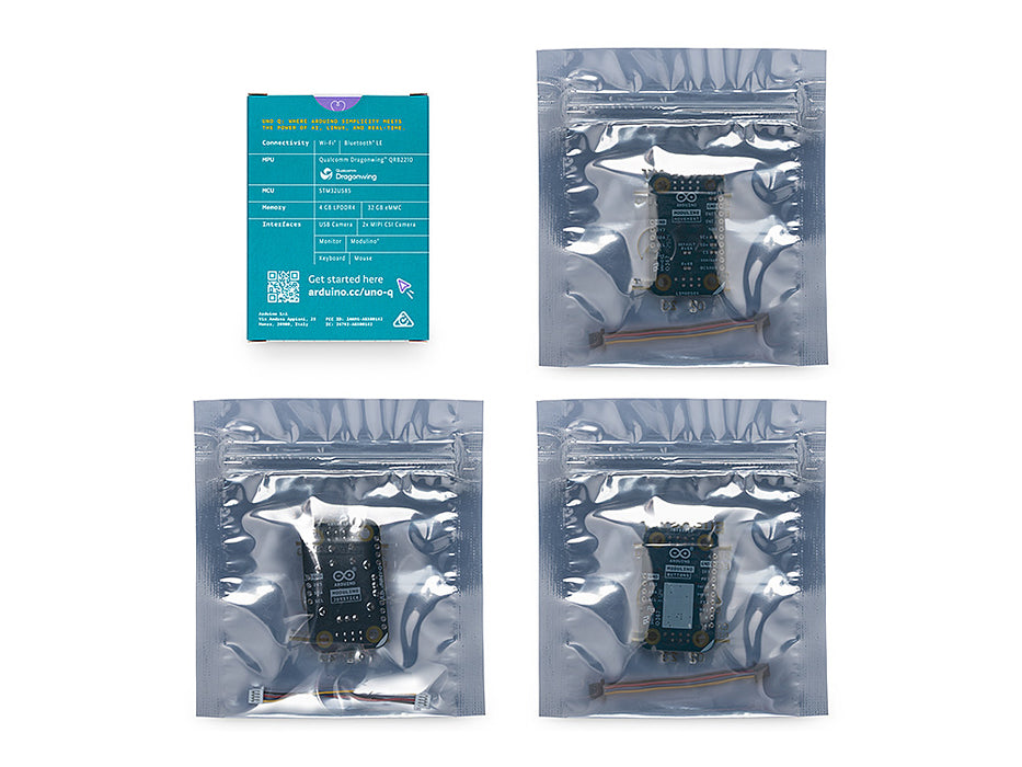 A top-down overview of the packaged components for the Arduino UNO Q Arcade Bundle on a white surface. The blue retail product box with detailed specifications is positioned top-left. To its right are three sealed silver static-shielding bags: one large bag containing the main UNO Q microcontroller board, and two smaller bags containing the arcade thumb joystick module and the push-button modules, each with their connecting cables
